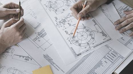 Colleagues reviewing printed plans around a table
